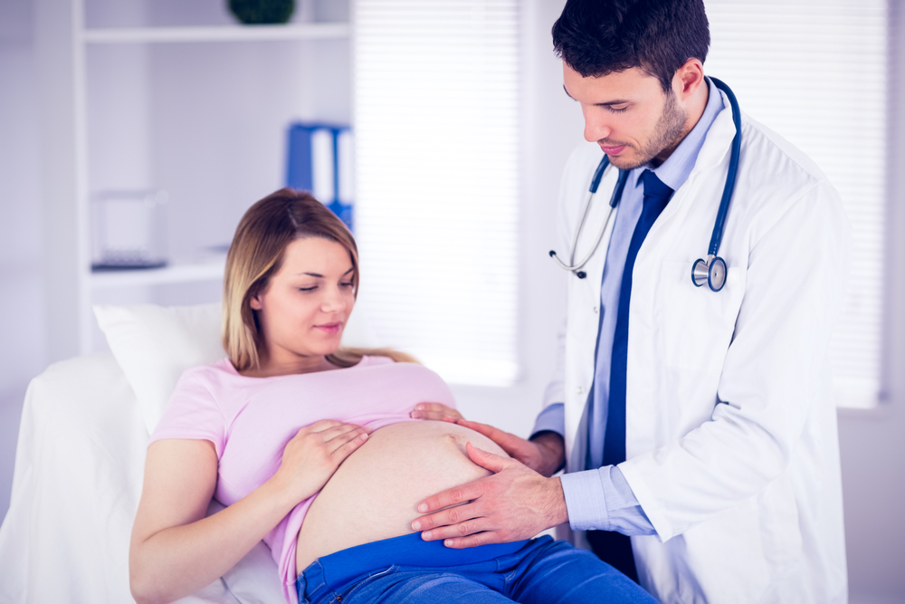 maternity care with pregnant mother and doctor examining belly